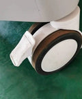 Badass Heavy Duty Trolley Casters Featuring Slick Polyurethane Wheels And Rock Solid Double Rotary Brakes For Furniture And Medical Equipment Rolling Smoothly close-up of swiveled caster with brake on a green surface.
