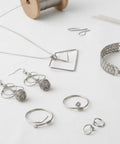 Silver-tone jewelry findings set: hooks, rings, chain, wire-frame pendant, and bracelet components.