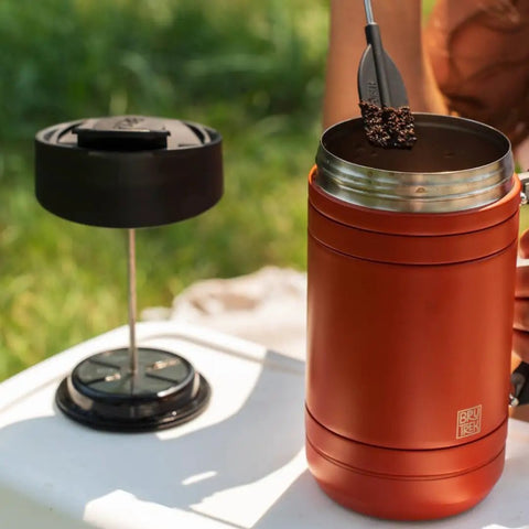 Insulated French Press Keeps Your Daily Joe Hella Hot For Hours With Tough Stainless Steel Build And Secure Twist Lid Crafted For Cabin Weeks And Backyard Chillin 32 Fl Oz Red Rock, showing coffee grounds being added.
