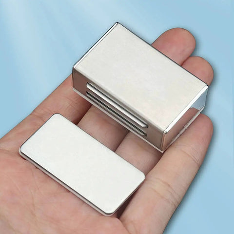 Hand holding No Drill Adhesive Magnetic Door Catch Set 17lb Holding Force For Kitchen Cabinets Cupboards And Drawers Self Stick Stainless Steel Latch 4 Pack Silver Damage Free Mounting