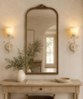 Folux Battery-Operated Vintage White Flower Wall Sconce Set of 2 illuminating a mirror above a wooden console table.