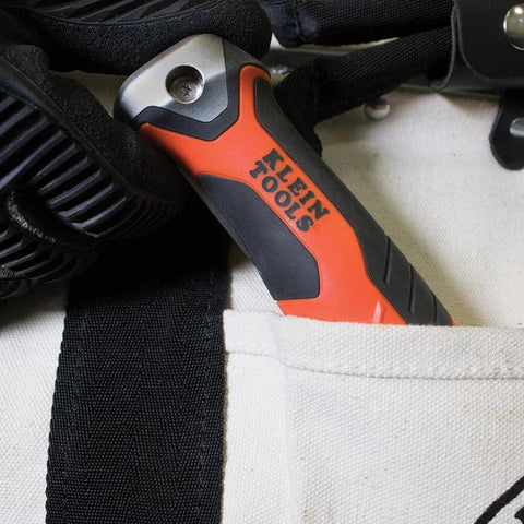 Klein Tools folding jab saw handle in orange and black, shown in a beige fabric pocket.