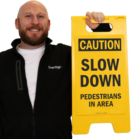 Caution Slow Down Pedestrians In Area Folding Floor Sign 25 By 12 Inches Plastic Black On Yellow Big And Bright Double Sided Durable Sign With Easy Carry Handle For Indoor Or Outdoor Use.