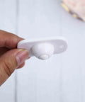 Holding a white 4 Pcs Self Adhesive 360 Degree Swivel Caster Wheel, showing durable ABS construction with adhesive backing.