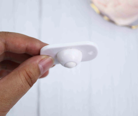 Holding a white 4 Pcs Self Adhesive 360 Degree Swivel Caster Wheel, showing durable ABS construction with adhesive backing.