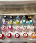 Drawer with colorful spools of thread neatly organized in rows, showcasing various shades for sewing and crafting projects.