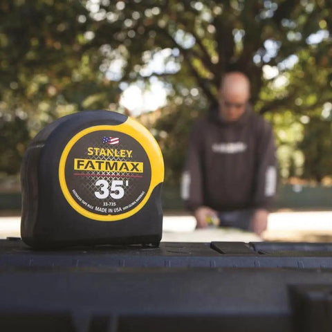 35 Foot Tape Measure With BladeArmor Coating On First 6 Inches, close-up showing front branding in front of blurred worker