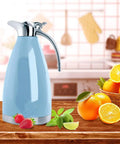 68 Oz Stainless Steel Coffee Carafe With Double Wall Vacuum Insulation Keeps Your Brew Hot Up To 12 Hours Or Cold Up To 24 Hours, 2 Liter Capacity, Blue on kitchen counter with citrus fruits.