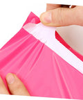 Hands sealing Thickened Waterproof Pink Poly Mailer Bags 17x30cm Bulk Pack of 100, showing durable adhesive closure