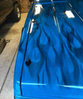 Blue truck hood with flame design in garage setting.