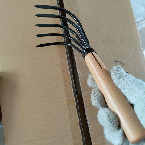 Japanese Ninja Claw Rake And Cultivator 5 Prong Garden Tool With Wood Handle held above cardboard box