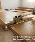 QWORK hardwood flooring jack and positioning tool on a wood floor; brass metal with ratcheting handle, gloved hand
