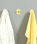 Top Shelf Brass Wall Hooks For Towels And Mugs No Sweat Rust Proof Bathroom Hanger holding white and yellow towels on wall.