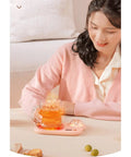 Portable Digital Cup Warmer With Three Heat Settings Hits The Spot Every Time Keeps Your Daily Brew Steaming Hot on a pink coaster with tea.