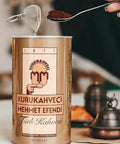 Can of Authentic Turkish Coffee From Mehmet Efendi Tradition, 100 Percent Arabica Ground Extra Fine For Cezve, Rich Aroma, Medium Roast, Classic Brew Since 1871, 17.6 Oz Bag with spoon and cezve in background