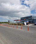Heavy Duty Flexible Bollard Built Damn Tough For Busy Parking Lots Takes Serious Beating And Springs Back orange and white traffic barrier in use on road.