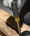 Gloved hand using Grab And Go Multi Bit Tamperproof Screwdriver Kit With Twenty Six Onboard Bits And Quarter Inch Nut Driver on wood