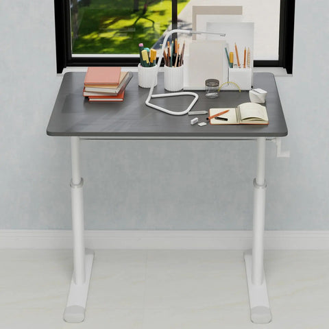 No Fuss Manual Crank Standing Desk That Dials Height Quick For Smooth Sit To Stand Workstation Killer Ergonomic Computer Desk For Tight Quarter Home Office Setup In Modern Charcoal Gray with books and lamp on top.