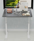 Game Changer Manual Crank Height Adjustable Standing Desk 32X24 Inch in a bright room with office supplies on top.