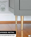 Gold Tapered Oblique Metal Furniture Leg Set Of 4 16 Inch Mid Century Modern Replacement Feet For Chairs Coffee Tables And Cabinets Heavy Duty Build Easy Install For DIY Upgrades shown supporting grey cabinet on wooden floor.