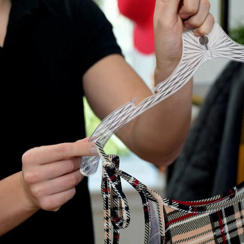 Close-up of a person holding a heavy duty plastic clothes hanger with a shirt on it. Part of Heavy Duty Plastic Clothes Hangers Set Of 12 For Wardrobe Organization Space Saving Crystal Clear Hangers For Shirts Blouses Dresses T Shirts Tees And Coats Ideal For Men And Women Closet Makeover.