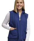 Woman wearing a navy zip front scrub vest with detachable hood and pockets. Zip Front Scrub Vest With Detachable Hood For Women