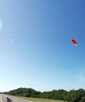 B3 Light Traction 3 Meter Kite for Kiteboarding in flight over open road and clear sky, person holding kite bar on roadside