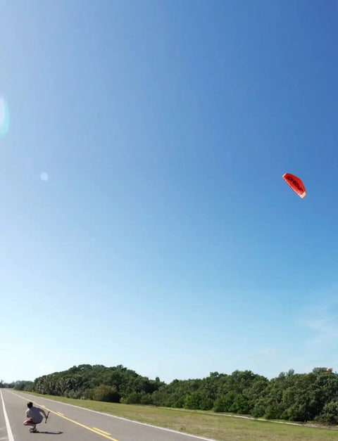 B3 Light Traction 3 Meter Kite for Kiteboarding in flight over open road and clear sky, person holding kite bar on roadside