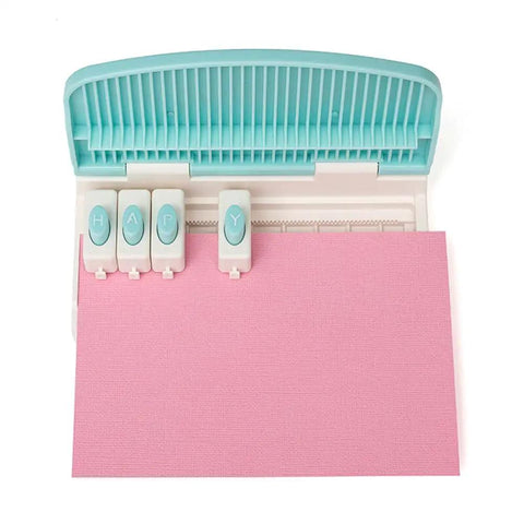 Top view of Word Punch Board For Scrapbooking And Card Making Dope Letter Punch Set With 26 Letters punching 'HAPY' on pink paper.