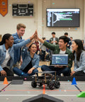 OSOYOO FlexiRover robot car kit on a gym floor track; laptop shows code as students cheer.