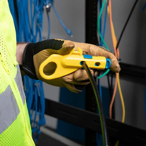 Gloved hand using Data And Coax Cable Stripping Tool With Radial Design For RG59 RG6 And CAT3 To CAT6A in networking setup.