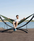 Set Up In 3 Seconds Adjustable Portable Aluminum Hammock Stand For Outdoors With Chair Mode And Lounge Mode Up To 105 Inches Ideal For Backyard Patio Beachside Chill And Easy Snap Fold Assembly with a person relaxing on a dock.
