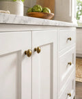 Top Shelf Antique Brass Cabinet Knobs Six Pack Round Single Hole Kitchen Furniture Hardware Easy DIY Install Vintage Inspired aged brass knobs on a white kitchen cabinet.