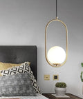 BEQAOR Modern Globe Pendant Light, 1-Light Oval Hoop Hanging Ceiling Fixture with Frosted White Glass Shade and Gold Finish Frame for Bedroom Bedside above a bed with pillows.