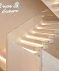 Modern staircase with glass railing and 'U was all a dream' neon sign on wall; interior decor featuring ambient lighting.