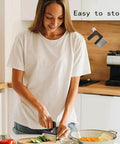 Front view of a woman using a stainless-steel crinkle-cut veggie cutter to slice vegetables on a wooden cutting board.