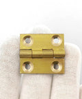Ten Pack 1 Inch Brass Butt Hinges With Screws For Cabinets Drawers And Jewelry Boxes DIY Friendly Durable Solid Brass Rust Proof Easy Install Heavy Duty Hardware Kit By Quweiz shown in a hand close-up.