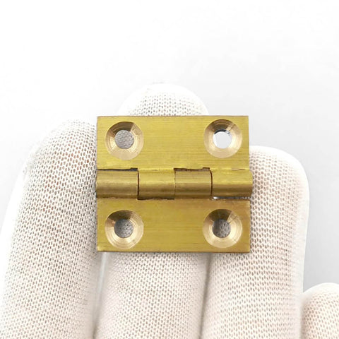 Ten Pack 1 Inch Brass Butt Hinges With Screws For Cabinets Drawers And Jewelry Boxes DIY Friendly Durable Solid Brass Rust Proof Easy Install Heavy Duty Hardware Kit By Quweiz shown in a hand close-up.
