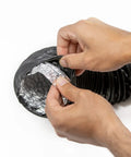 Hands peeling back black PVC to reveal aluminum interior on 4 Inch Flexible PVC Reinforced Aluminum Dryer Duct 10 Feet For Front Load And Top Load Dryers.