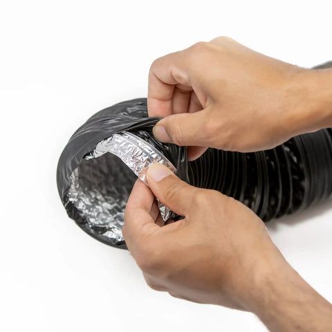 Hands peeling back black PVC to reveal aluminum interior on 4 Inch Flexible PVC Reinforced Aluminum Dryer Duct 10 Feet For Front Load And Top Load Dryers.