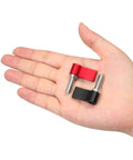 Close-up of a hand holding two thumb screws; 10 Pack M6 17mm Thumb Screws With Handle Red Rotating Knob Adjustable Lever Single Wing Easy Install No Tools Required Great For Furniture Decor Photography Gear And Electronic Equipment. One screw is black, and one is red, showing the rotating knob.