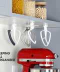 Installed Four Pack Stand Mixer Attachment Organizer For KitchenAid Accessories With Flex Edge Beater Flat Beater Dough Hooks And Wire Whip Universal Holder Rack For Grab And Go Access And Kitchen Counter Space under a kitchen cabinet, holding mixer attachments.