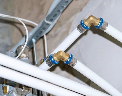 25 Pack Half Inch Brass PEX Fittings Set Includes 90 Degree Elbows For PEX Tubing Durable Potable Water Approved 2014 SDWA Compliant Easy Install Ideal For Home Plumbing Projects shown in plumbing setup with white PEX tubing.