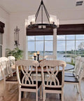 5 Light Black Farmhouse Chandelier for Dining Room and Foyer, hanging above wooden dining table with glass shades, wagon wheel shape.