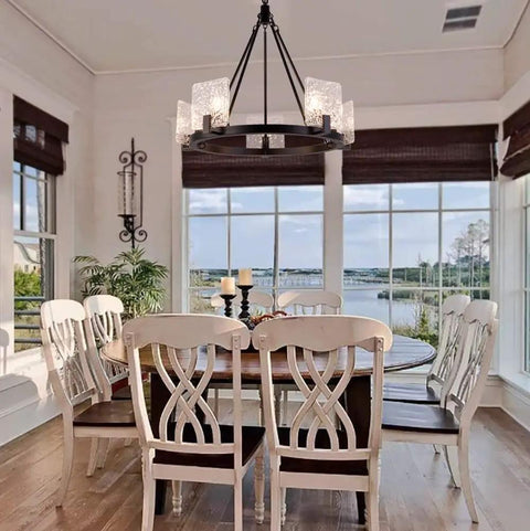 5 Light Black Farmhouse Chandelier for Dining Room and Foyer, hanging above wooden dining table with glass shades, wagon wheel shape.