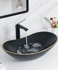 Large Matte Black Oval Vessel Sink With Gold Trim And Pop Up Drain For Above Counter Bathroom Use, Ceramic with water flowing from faucet