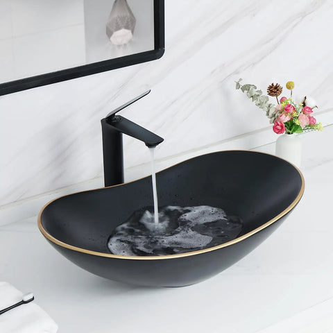 Large Matte Black Oval Vessel Sink With Gold Trim And Pop Up Drain For Above Counter Bathroom Use, Ceramic with water flowing from faucet