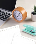 Grab And Go Handheld One Quarter Inch Hole Punch For Up To Twenty Sheets, Metal Hole Puncher With Skid Resistant Base For Paper Chipboard And Art Projects, Green next to a laptop, clock, and plant.