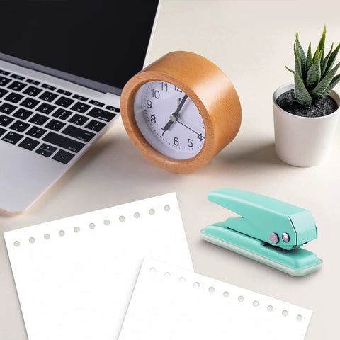Grab And Go Handheld One Quarter Inch Hole Punch For Up To Twenty Sheets, Metal Hole Puncher With Skid Resistant Base For Paper Chipboard And Art Projects, Green next to a laptop, clock, and plant.