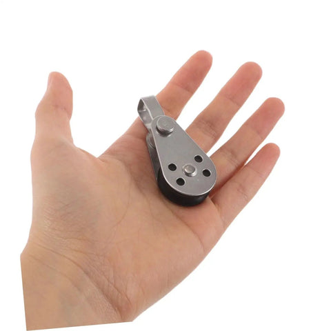Hand holding a small stainless steel sailing pulley block with bearings, part of a 4 pack for marine rope pulleys kayak and boat anchor utility.